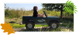 Girl driving a mini Land Rover over a rumble strip in the park