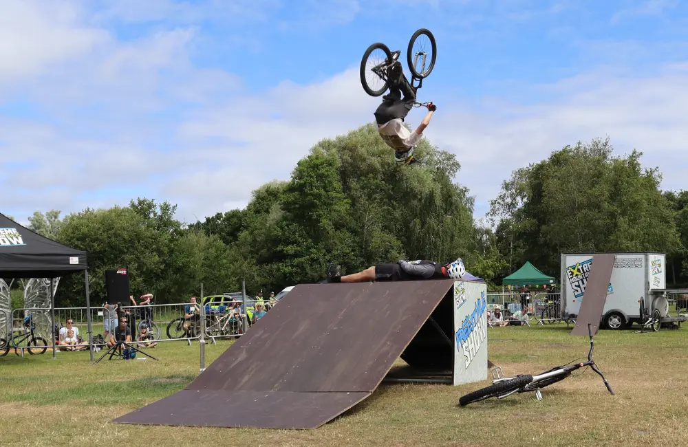 stunt rider back flipping over ramp on pedal bike