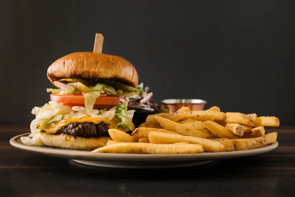 A Seasons cheeseburger with lettuce and tomato, served on a plate with French fries and a side of coleslaw.